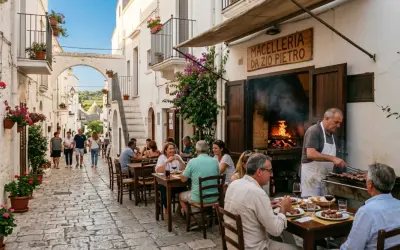 Cosa vedere a Cisternino in mezza giornata: vicoli bianchi, fiori colorati e un macellaio che griglia carne all'aperto.