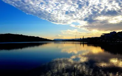Tramonto sui Ganzirri, con cielo nuvoloso e riflessi dorati sull'acqua. Un luogo incantevole da esplorare.