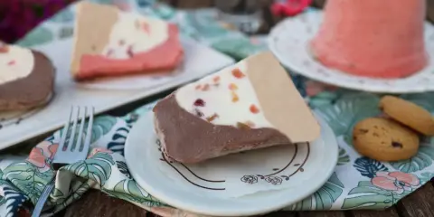 Fette di gelato a pezzo siciliano, con cioccolato, crema e frutta candita, servite su piattini con tovaglioli floreali.