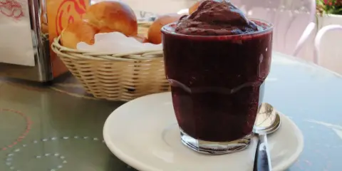 Un bicchiere di granita messinese, scura e invitante, accanto a soffici brioche in un cestino. Un'immagine che sa di sole e colazioni siciliane.