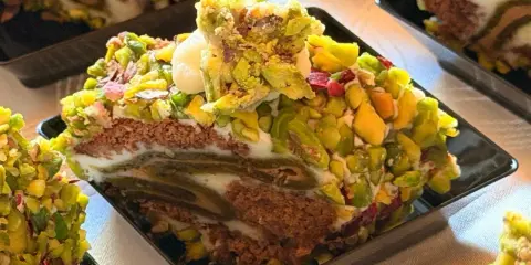 Fetta di rollò nisseno ricoperta di pistacchi e crema. Un dolce invitante e colorato.