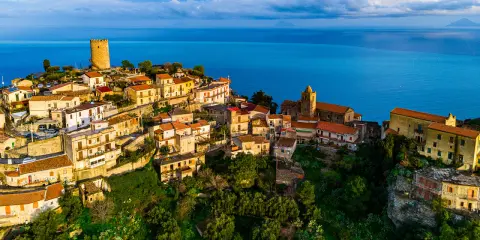 Panoramica aerea di Piraino, borgo siciliano arroccato sul mare. La terrazza naturale offre una vista mozzafiato sul blu intenso dell'acqua.