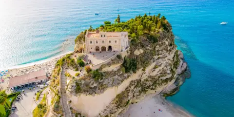 Santuario di Santa Maria dell'Isola a picco sul mare turchese, un must per chi cerca cosa fare a Tropea. Spiaggia e panorama mozzafiato.