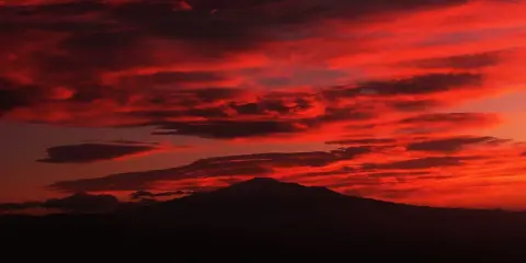 Tramonto infuocato sull'Etna, un vulcano maestoso che domina il paesaggio. Etna iddu, un'icona siciliana.