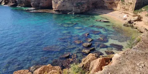 Acque cristalline e scogliere dorate incorniciano la spiaggia di Massolivieri, un angolo di paradiso con rocce affioranti.