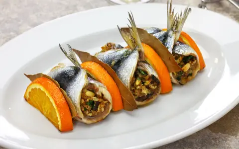Sardine ripiene, un'esplosione di sapori mediterranei, tra le specialità siciliane salate. Arancia, alloro e un ripieno gustoso.