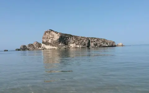 La Rocca San Nicola a Licata, imponente roccia calcarea che emerge dal mare cristallino, sotto un cielo azzurro.