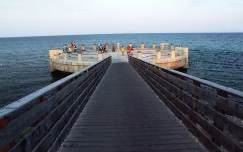 Passeggiata sul lungomare di Avola di sera, con persone che si godono la vista dal molo circolare.