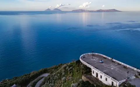 La guardiola Piraino domina il mare blu cobalto. All'orizzonte, le isole Eolie emergono dalla foschia.