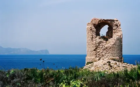 Torre saracena in rovina, un luogo suggestivo da scoprire a Terrasini, con il mare blu e le montagne sullo sfondo.