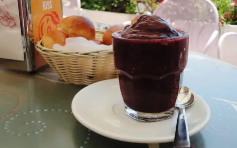 Un bicchiere di granita messinese, scura e invitante, accanto a soffici brioche in un cestino. Un'immagine che sa di sole e colazioni siciliane.