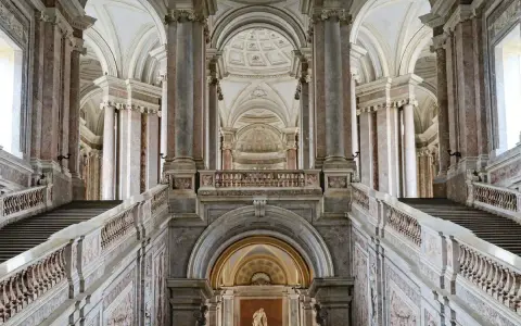 Magnifici interni della Reggia di Caserta: scalinate imponenti, marmi pregiati e volte maestose creano un'atmosfera regale.