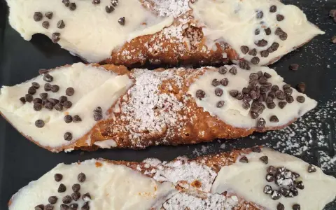 Cannoli siciliani, un classico di cosa si mangia in Sicilia: croccanti cialde ripiene di crema e gocce di cioccolato.