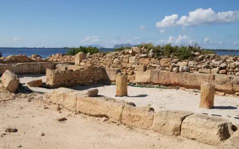 Rovine antiche a Mozia, cosa vedere: resti di mura e colonne di pietra con il mare sullo sfondo sotto un cielo azzurro.