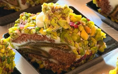 Fetta di rollò nisseno ricoperta di pistacchi e crema. Un dolce invitante e colorato.