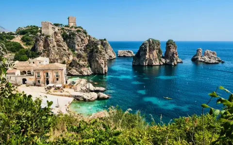 Baia con faraglioni e torri antiche, ideale per scoprire come arrivare a Scopello e godersi il mare cristallino.