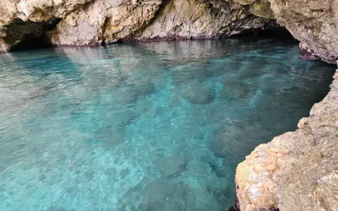 Acque cristalline nella baia di San Cataldo, con rocce calcaree che creano un'atmosfera suggestiva.