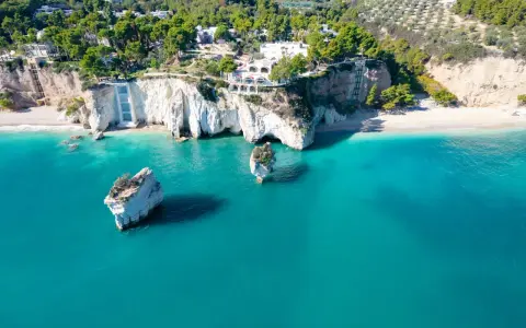 Scogliere bianche a picco sul mare turchese, con rocce isolate e vegetazione lussureggiante. Un vero angolo di paradiso tra le spiagge più belle della Puglia.