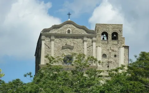 Chiesa Madre di Corleone, un gioiello di pietra con campanile e campane, tra il verde degli alberi. Un luogo da scoprire tra le cose da vedere a Corleone.