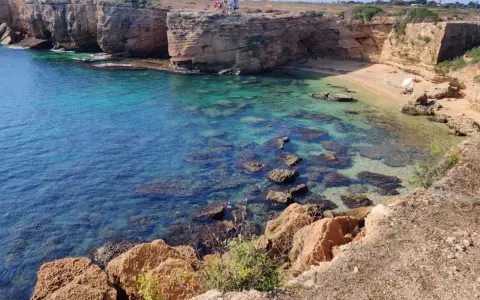 Acque cristalline e scogliere dorate incorniciano la spiaggia di Massolivieri, un angolo di paradiso con rocce affioranti.