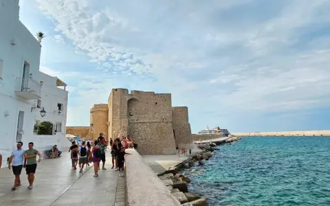 Passeggiata serale a Monopoli: il castello, il mare azzurro e una nave da crociera.