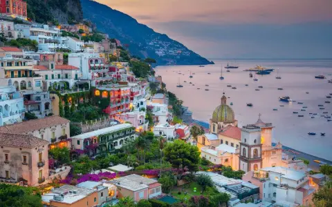 Vista mozzafiato dal **punto panoramico Positano**, con case colorate aggrappate alla scogliera e barche nel mare al tramonto.
