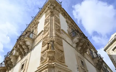 Angolo del palazzo Beneventano a Scicli, con balconi in ferro battuto e sculture barocche.