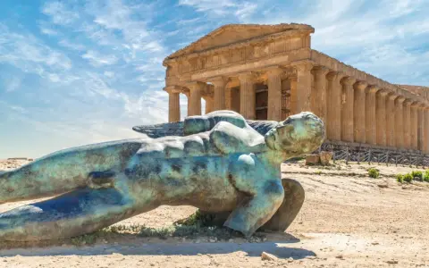 Statua di Icaro caduto nella Valle dei Templi, Agrigento. Il tempio dorico sullo sfondo è il Tempio della Concordia.