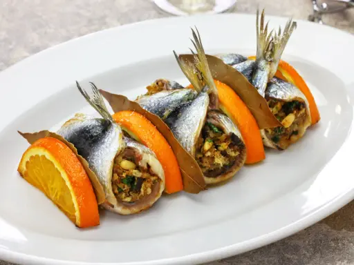 Sardine ripiene, un'esplosione di sapori mediterranei, tra le specialità siciliane salate. Arancia, alloro e un ripieno gustoso.