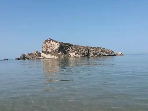 La Rocca San Nicola a Licata, imponente roccia calcarea che emerge dal mare cristallino, sotto un cielo azzurro.
