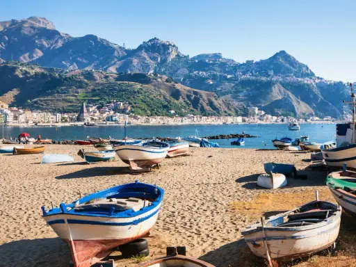 Barche da pesca sulla spiaggia di Giardini Naxos, con Taormina sullo sfondo montuoso.