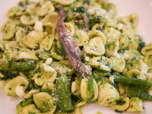 Orecchiette con cime di rapa, uno dei piatti tipici pugliesi primi, condite con acciughe e formaggio grattugiato.