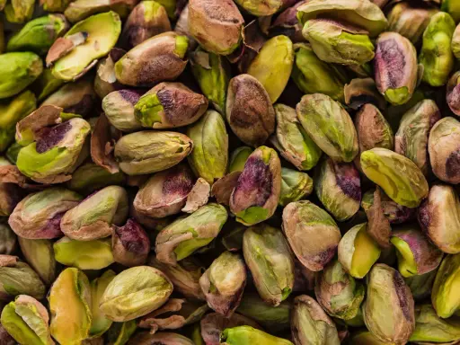 Un mucchio di pistacchi, alcuni con il guscio screpolato che rivela il loro interno verde brillante, ricordano il sapore del pistacchio in siciliano.