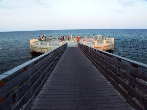 Passeggiata sul lungomare di Avola di sera, con persone che si godono la vista dal molo circolare.