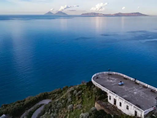 La guardiola Piraino domina il mare blu cobalto. All'orizzonte, le isole Eolie emergono dalla foschia.