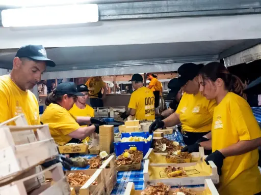 Persone in maglietta gialla servono fritto misto in un evento serale. Un'ottima idea per cosa fare a Salerno la sera, gustando specialità locali.