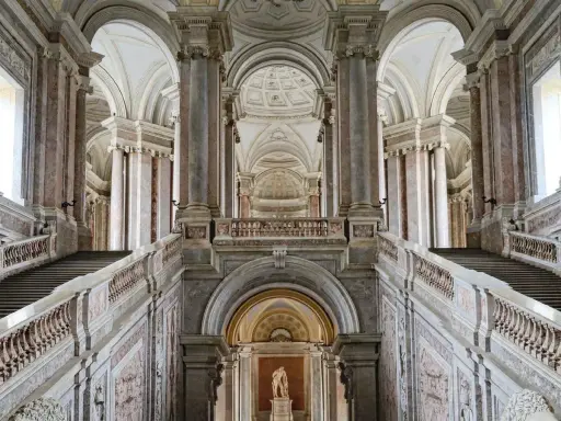 Magnifici interni della Reggia di Caserta: scalinate imponenti, marmi pregiati e volte maestose creano un'atmosfera regale.