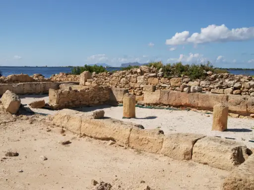 Rovine antiche a Mozia, cosa vedere: resti di mura e colonne di pietra con il mare sullo sfondo sotto un cielo azzurro.