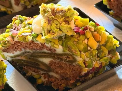 Fetta di rollò nisseno ricoperta di pistacchi e crema. Un dolce invitante e colorato.
