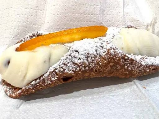 Cannolo ripieno di ricotta, uno dei dolci tipici di Palermo, cosparso di zucchero a velo e decorato con scorza d'arancia candita.
