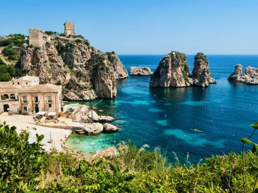 Baia con faraglioni e torri antiche, ideale per scoprire come arrivare a Scopello e godersi il mare cristallino.