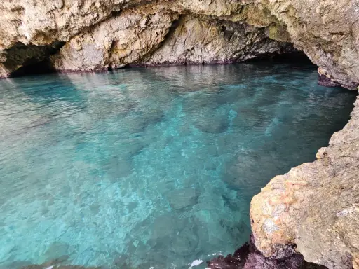 Acque cristalline nella baia di San Cataldo, con rocce calcaree che creano un'atmosfera suggestiva.