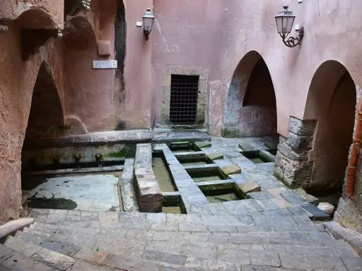 Antico lavatoio a Cefalù, con vasche in pietra e archi in rosa antico.
