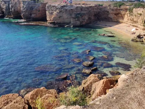 Acque cristalline e scogliere dorate incorniciano la spiaggia di Massolivieri, un angolo di paradiso con rocce affioranti.