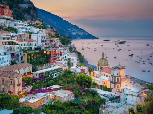 Vista mozzafiato dal **punto panoramico Positano**, con case colorate aggrappate alla scogliera e barche nel mare al tramonto.