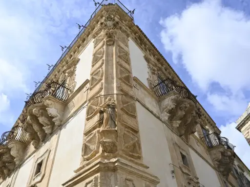 Angolo del palazzo Beneventano a Scicli, con balconi in ferro battuto e sculture barocche.