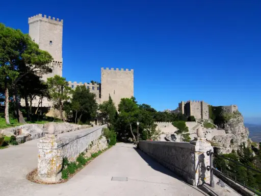 Erice: cosa vedere? Un antico castello domina il paesaggio, con torri imponenti e mura merlate che si stagliano contro il cielo azzurro.