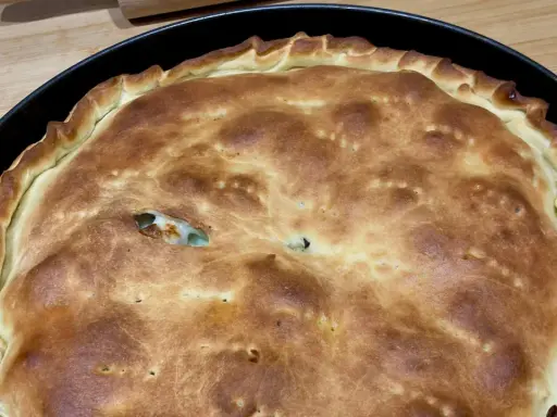 Schiacciatella pane dorata e fragrante, appena sfornata in teglia, con un ripieno invitante che fa capolino da una fessura.