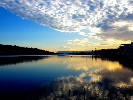 Tramonto sui Ganzirri, con cielo nuvoloso e riflessi dorati sull'acqua. Un luogo incantevole da esplorare.