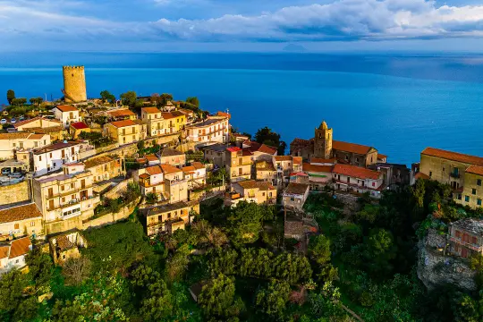 Panoramica aerea di Piraino, borgo siciliano arroccato sul mare. La terrazza naturale offre una vista mozzafiato sul blu intenso dell'acqua.
